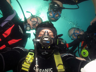 Dive Buddies pose for a group selfie underwater