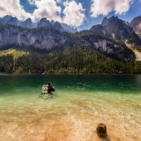 Diver with a double tank at the surface of a Swiss Lake with a mountain view at the background