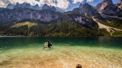 Diver with a double tank at the surface of a Swiss Lake with a mountain view at the background