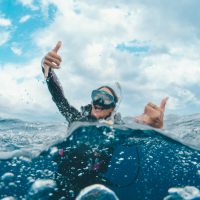 A diver celebrates at the surface with two shakas after a great dive