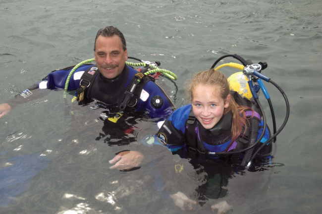 a father and daughter scuba diving in dry suits