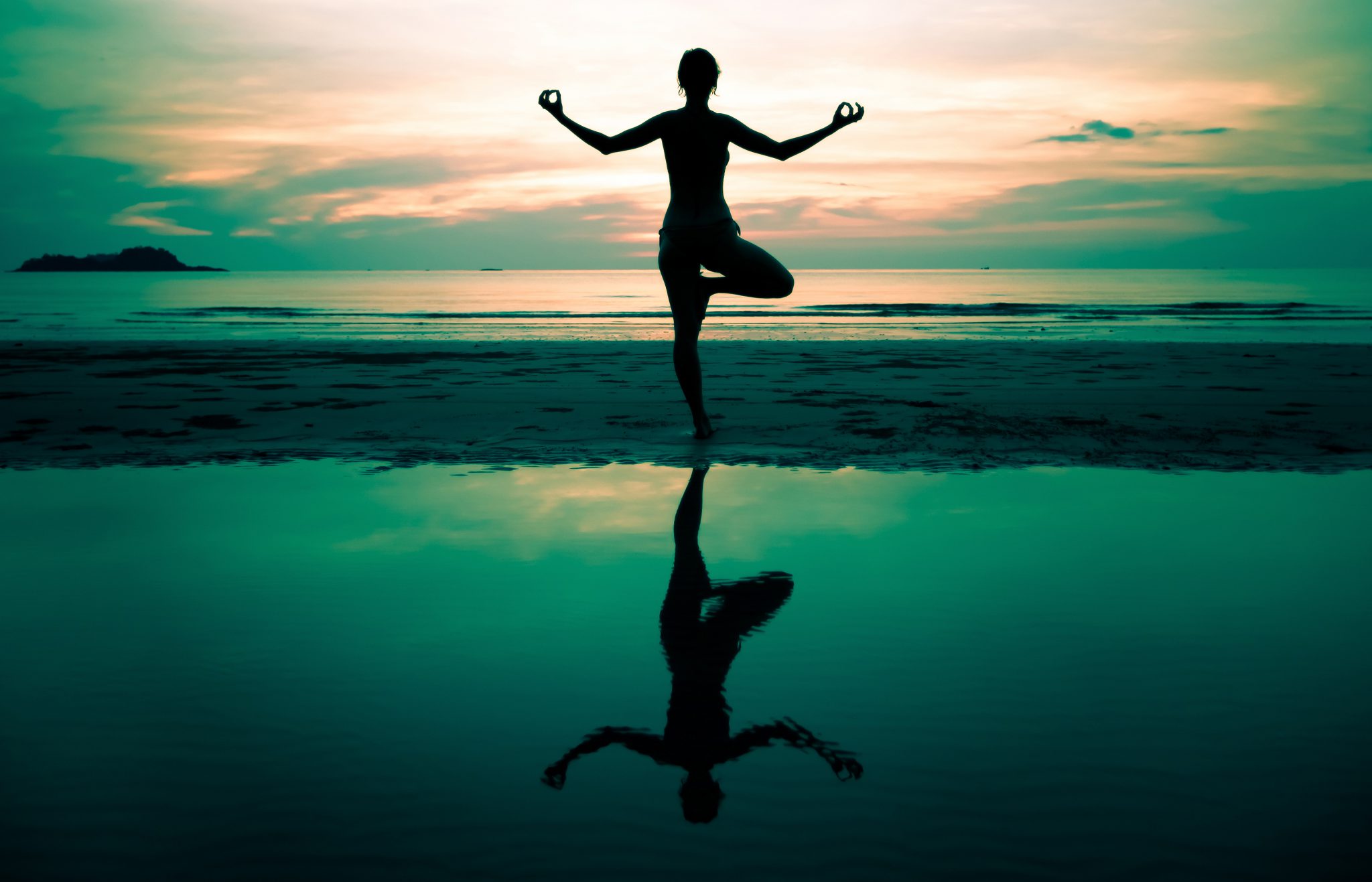 A silhouetted diver on the beach keeps fit before diving by doing yoga and knows you should never dive when tired or cold