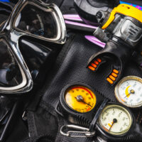 A dive mask and a regulator laid on a BCD and fins