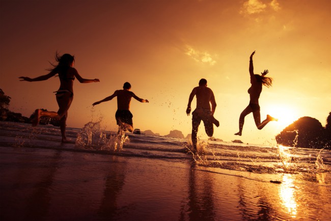 Amici insieme sulla spiaggia, correndo nell'oceano.