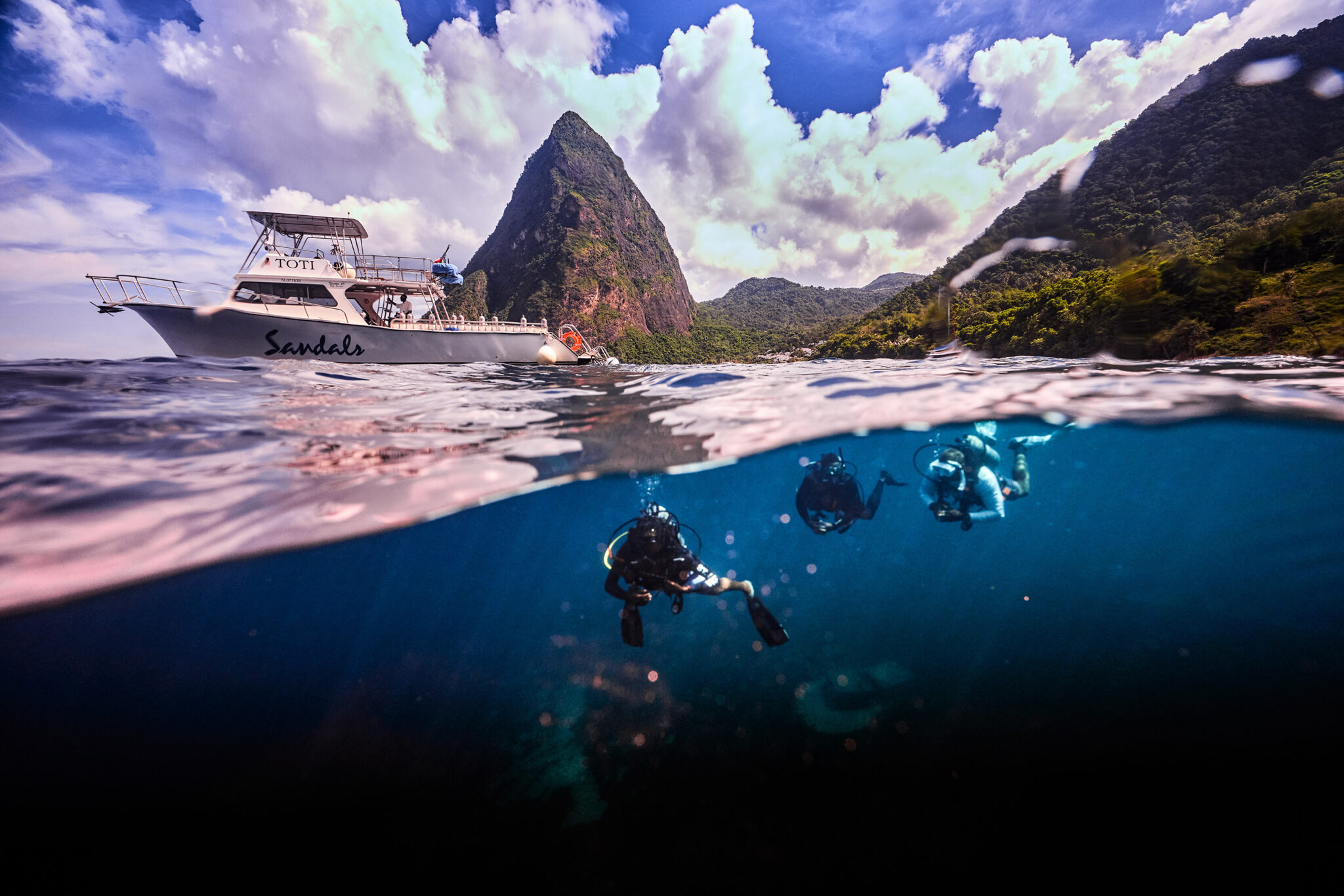 a split shot showing the pitons of st lucia at the top and scuba divers in the Caribbean sea at the bottom