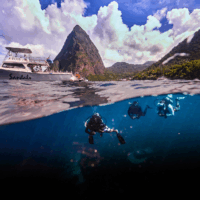 a split shot showing the pitons of st lucia at the top and scuba divers in the Caribbean sea at the bottom