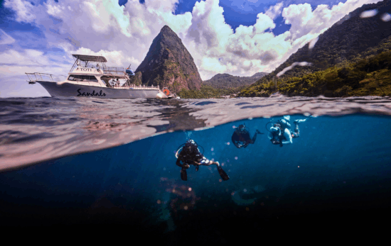 a split shot showing the pitons of st lucia at the top and scuba divers in the Caribbean sea at the bottom