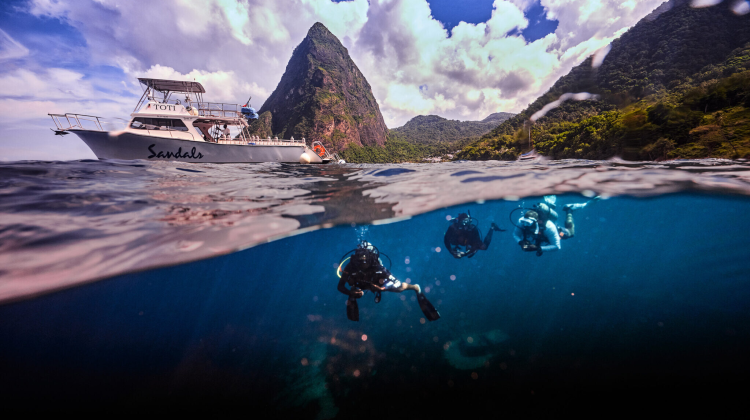 a split shot showing the pitons of st lucia at the top and scuba divers in the Caribbean sea at the bottom