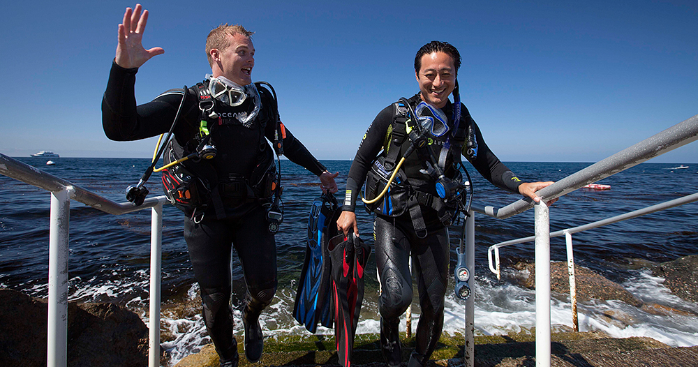 Two Advanced Open Water Divers exit the water on some concrete stairs