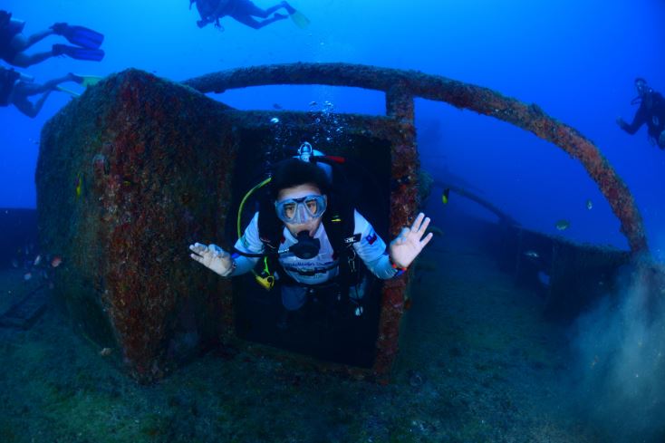 Octavio scuba diving through a wreck and giving the okay hand signal. 