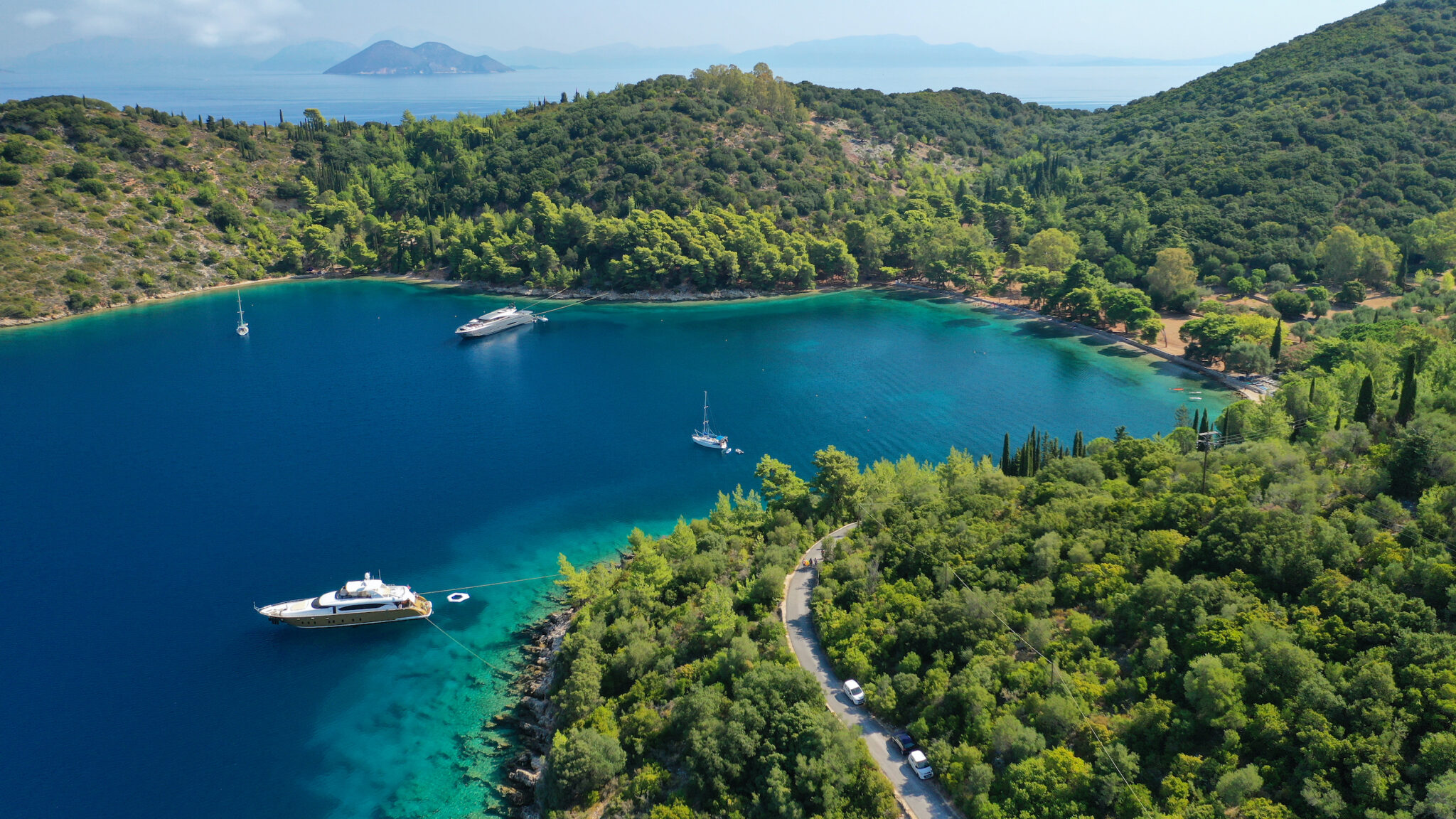 Liveaboard boats anchored in a flat, calm, stunning bay that look like they're straight out of a liveaboard guide brochure