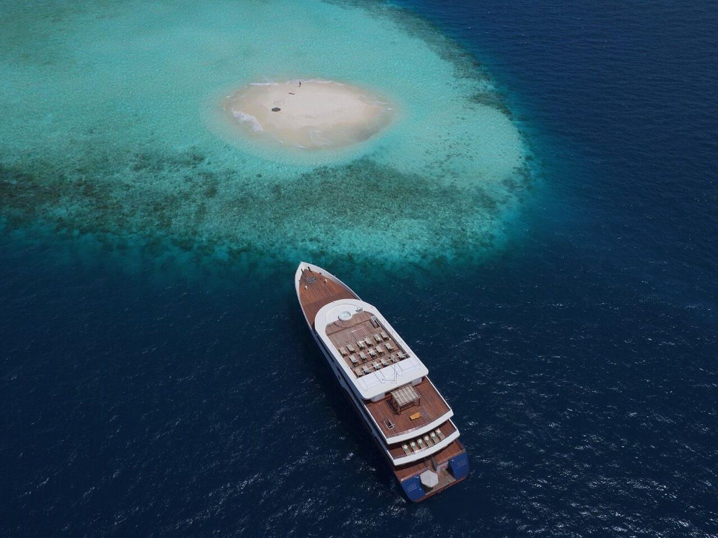 a liveaboard boat sits next to a reef in the Maldives