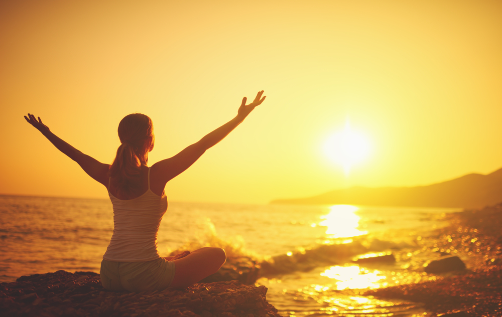 A woman at sunrise practicing yoga before a dive, which is a way to relax and how to overcome anxiety while scuba diving