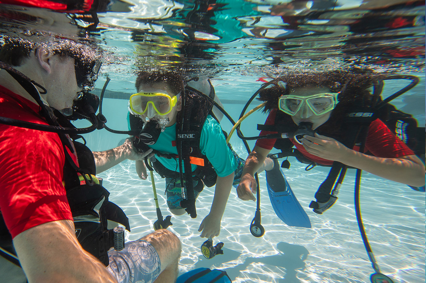 two kids get scuba diving lessons from a PADI Instructor in a swimming pool