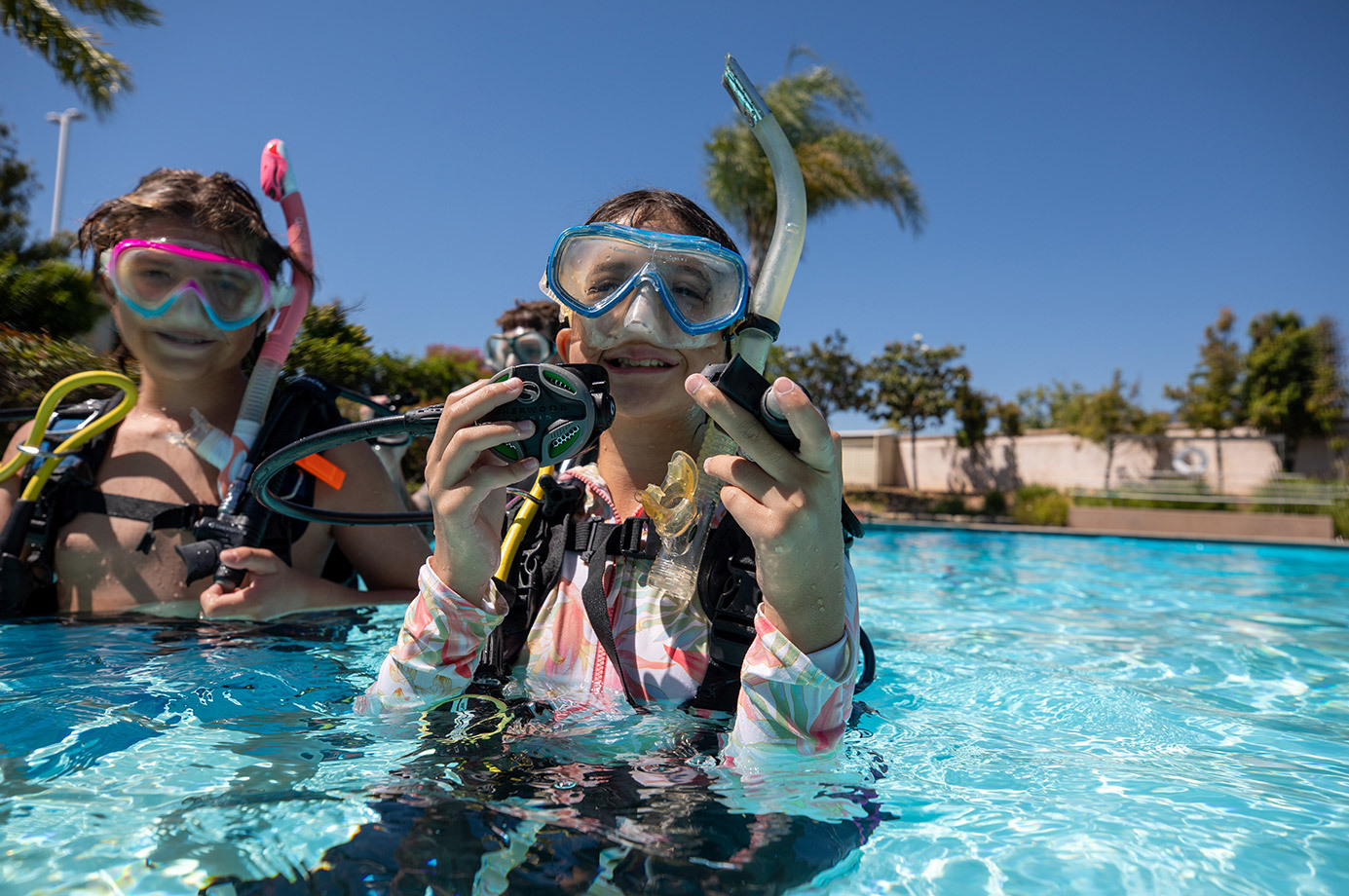 a young scuba diver adjusts her gear in a swimming pool