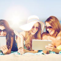 Friends on the beach with tablets from shutterstock