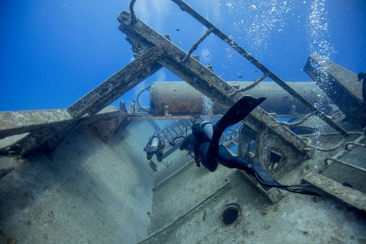 Dos Buceadores exploran un pecio bajo el agua.