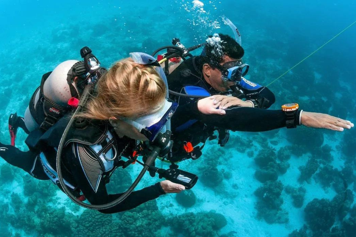 Scuba-instructeur helpt cursist met onderwaternavigatie.