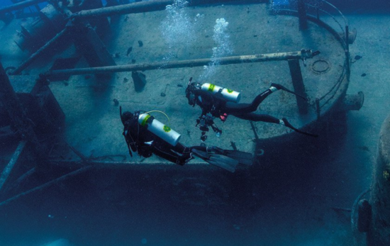 Two enriched air (nitrox) scuba divers exploring a wreck.