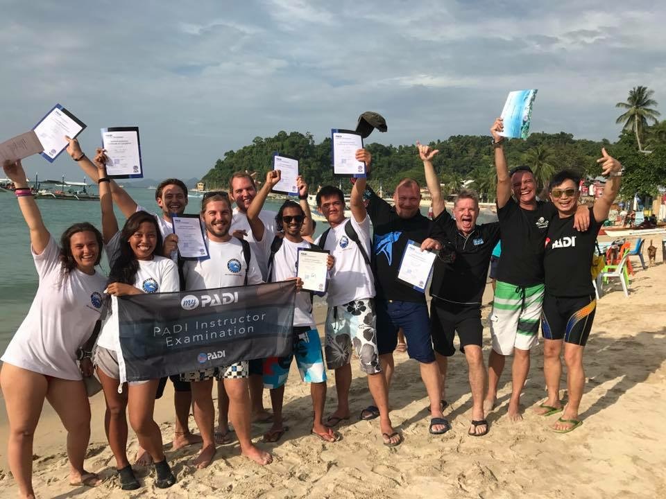 a group of new PADI Instructors smiling on a beach
