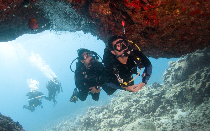 Taucher, die in eine Höhle schwimmen