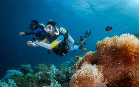 Two scuba divers diving with Nitrox, over a coral reef