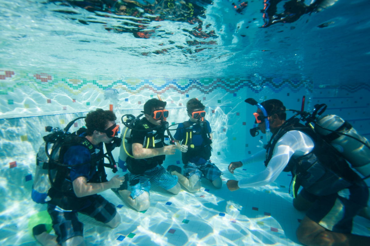 Kids taking a scuba diving course in a pool setting.