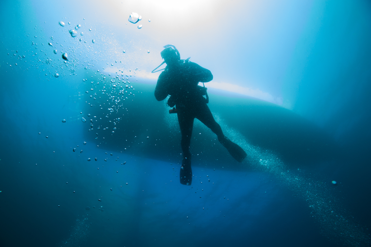 A diver descending from the dive boat into the water and who can minimize scuba diving dangers by following safe practices