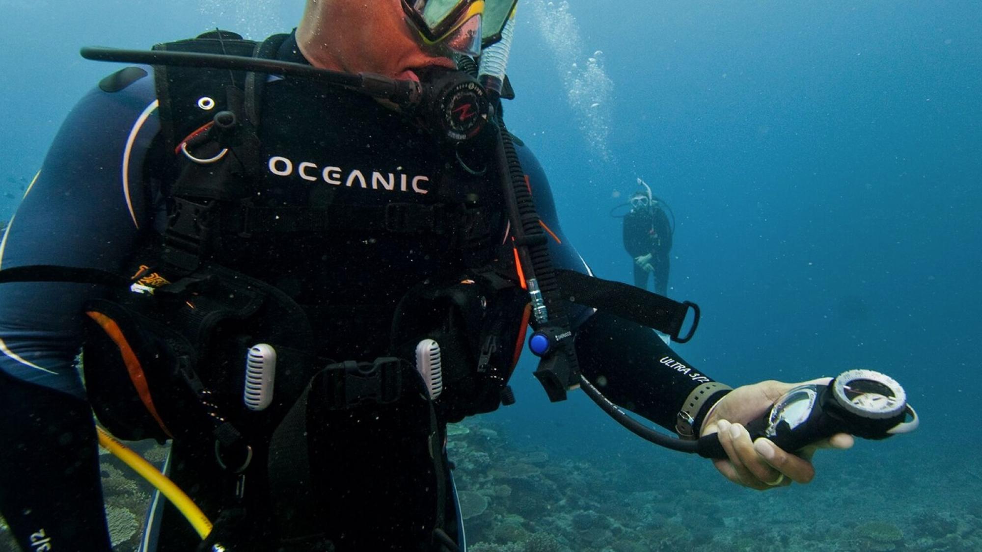 A scuba diver checking how much air he has left to breathe by reading his SPG (submersible pressure gauge) while underwater