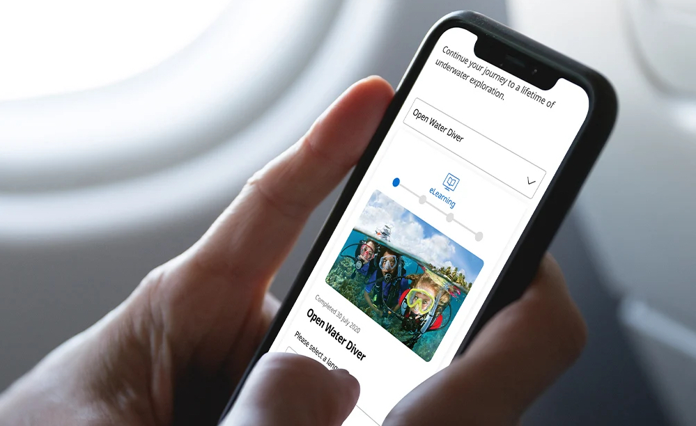 A diver accessing PADI eLearning from their mobile phone during a flight to a scuba destination
