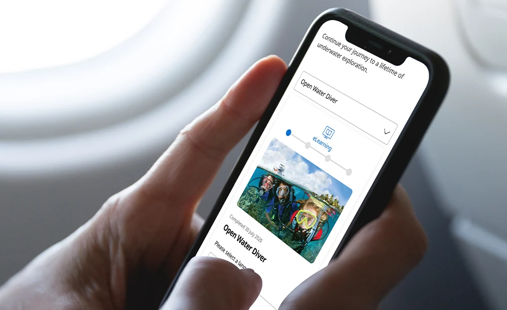 A diver accessing PADI eLearning from their mobile phone in order to study essential dive theory for PADI Open Water Diver