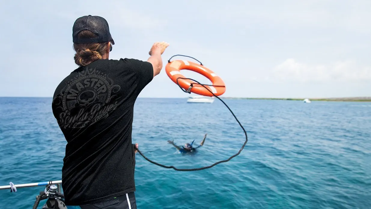 A person on the boat is throwing a life ring to a distressed diver at the surface.