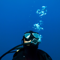 Scuba diver looking at scuba bubbles caused from exhaling underwater.