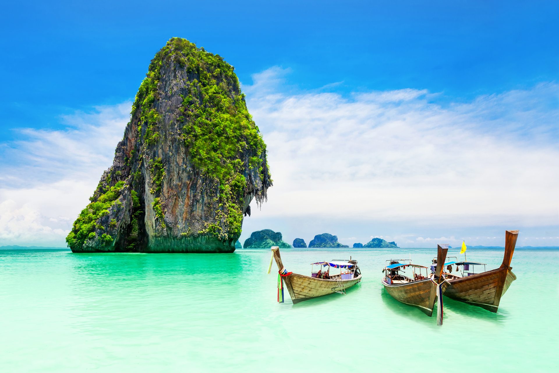 Longtail boats at a beach in Thailand, where clear water and white sand make it one of the best places to learn to scuba dive