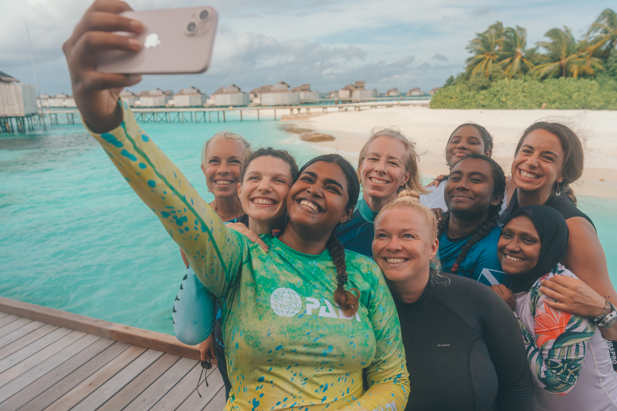 A group of female diveers in the maldives take a group selfie on a dock