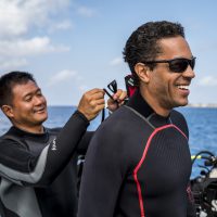 a diver zips up the wetsuit for his dive buddy