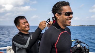 a diver zips up the wetsuit for his dive buddy