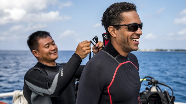 a diver zips up the wetsuit for his dive buddy