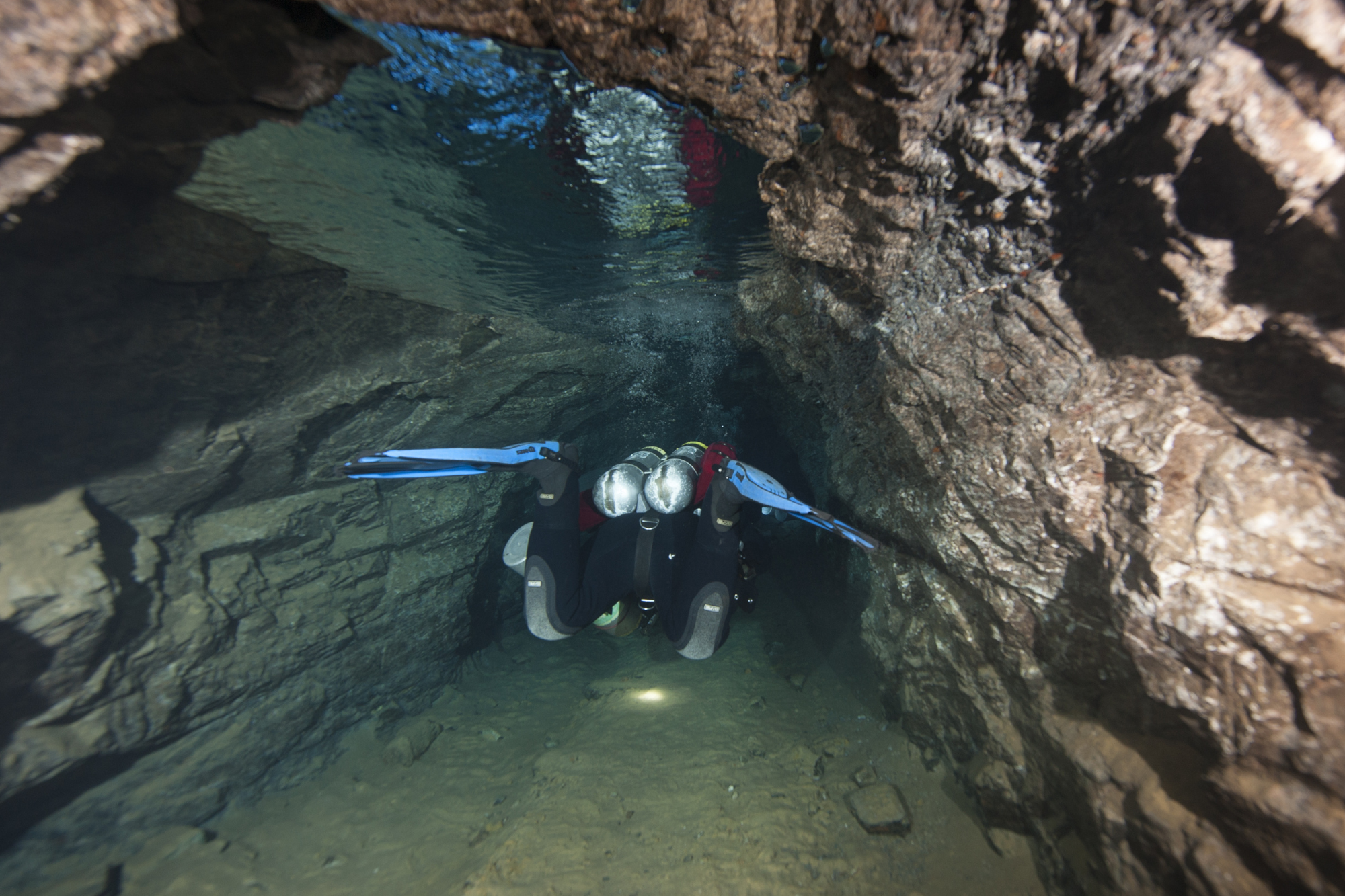 Scuba diver going through narrow passageway 