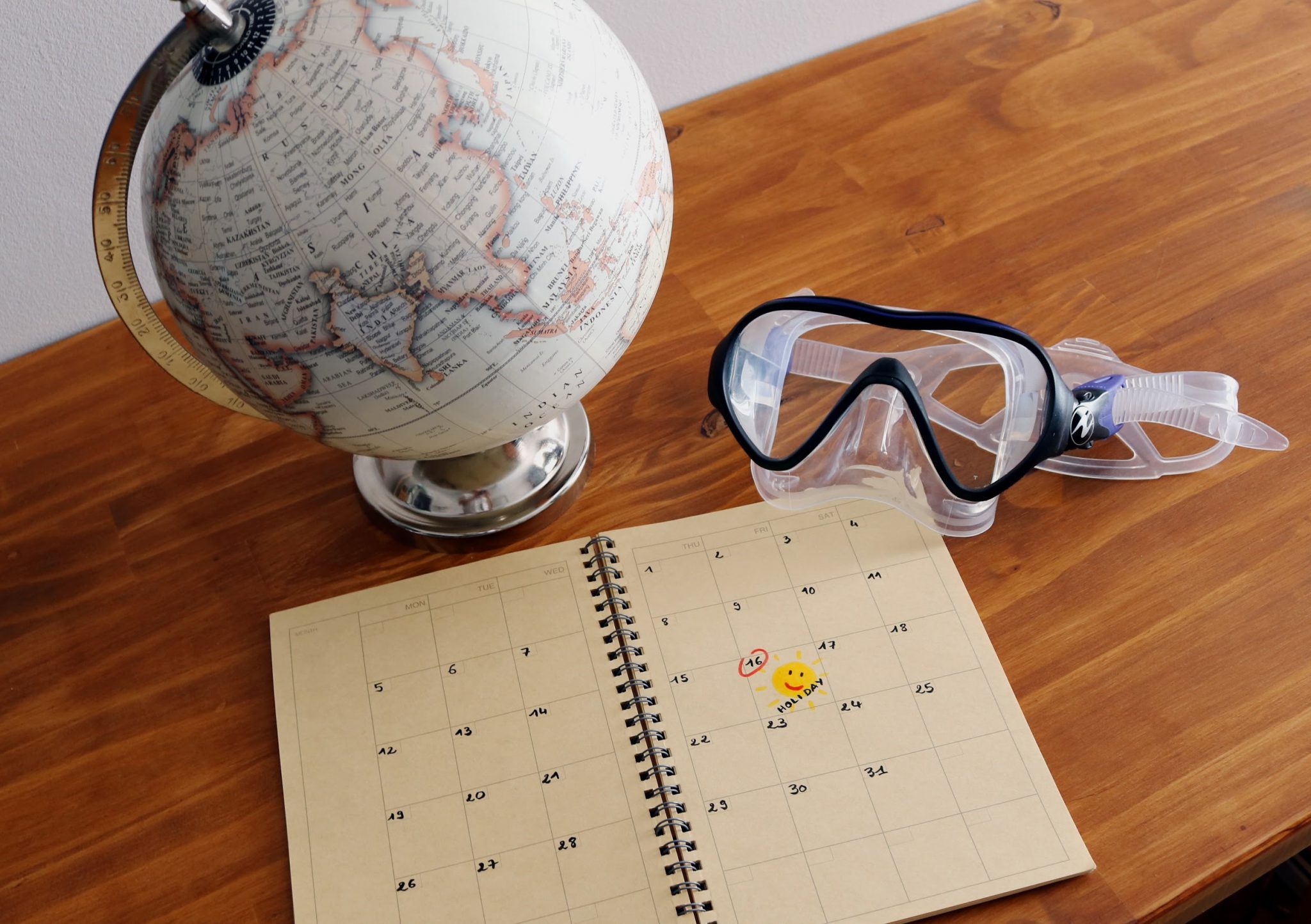 mask, planner and globe on a table Dive travel planning 
