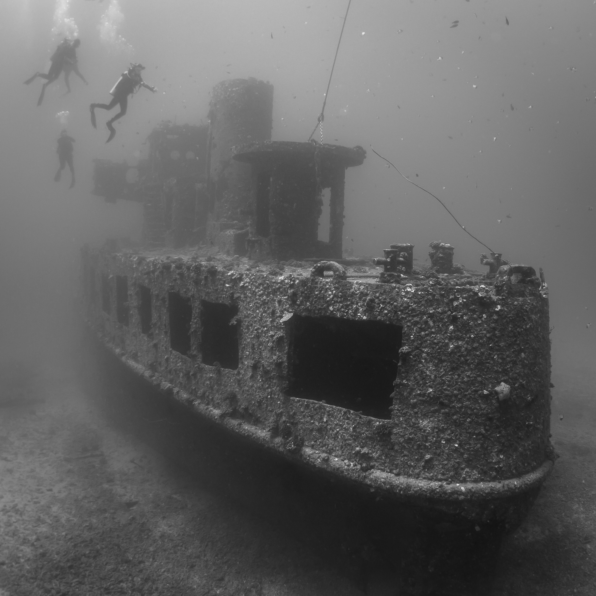 Scuba divers hovering above the YO-257 wreck near Waikiki City, which is one of the most popular Oahu diving destinations