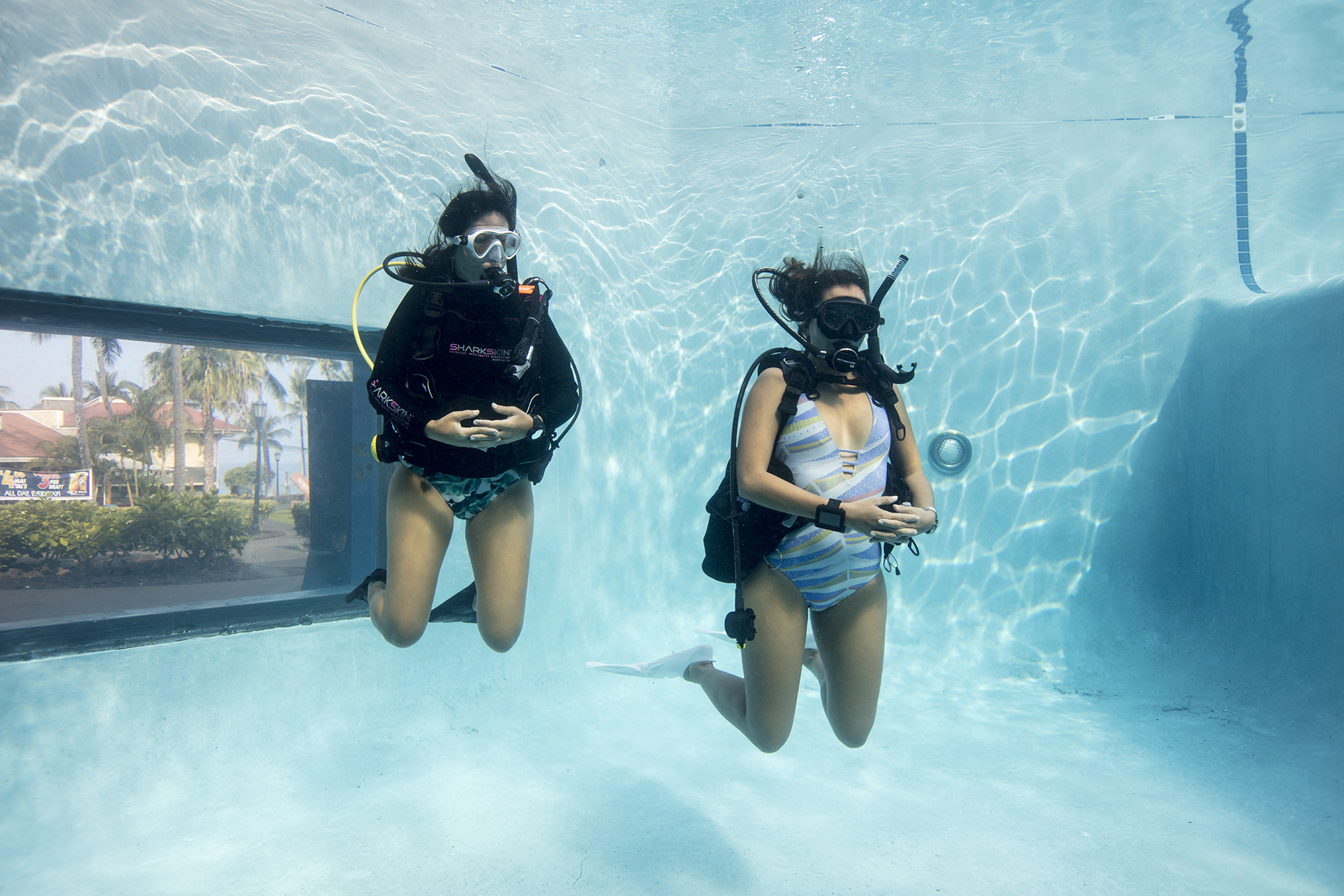 Dois mergulhadores fazendo um curso de mergulho autônomo em um ambiente de piscina.