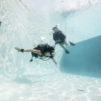 two divers in a pool practicing buoyancy