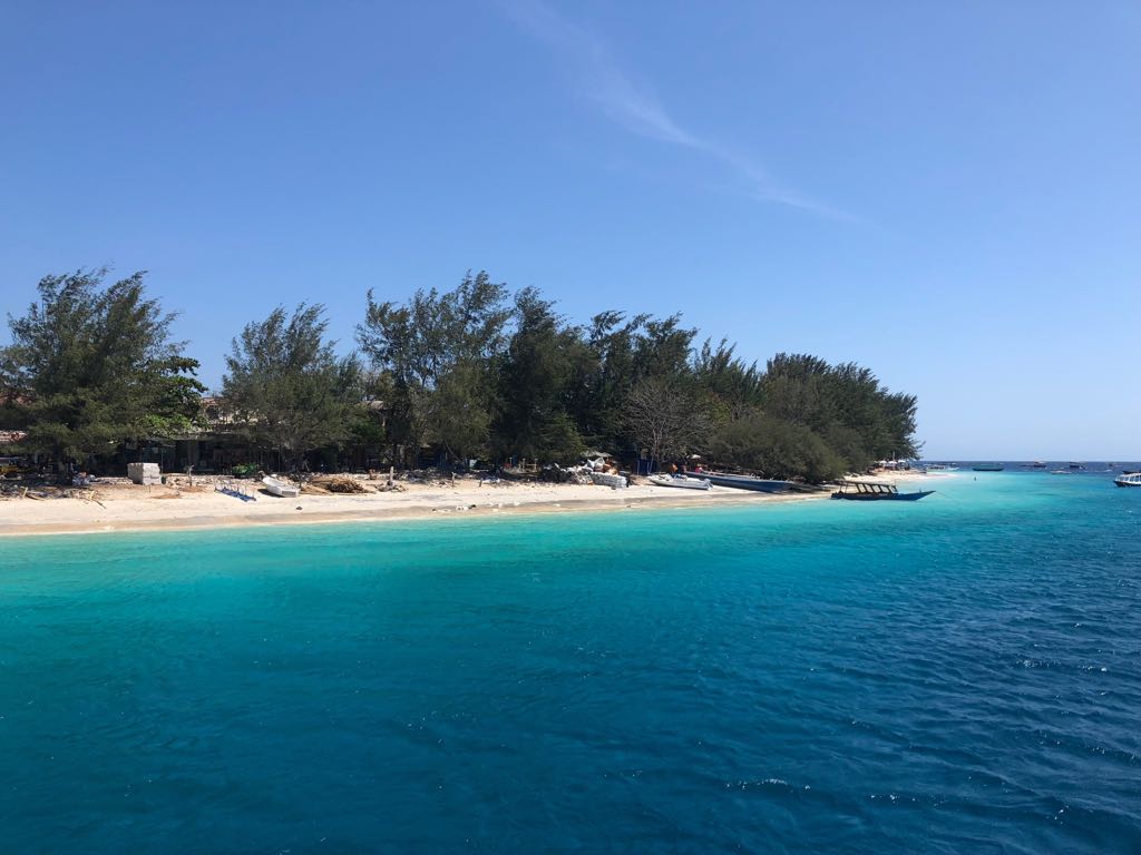 A sandy white beach and azure water surrounding one of the Gili Islands in Indonesia, one of the best places to go freediving