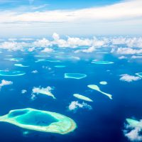 dozens of small atolls scattered across blue water in Maldives