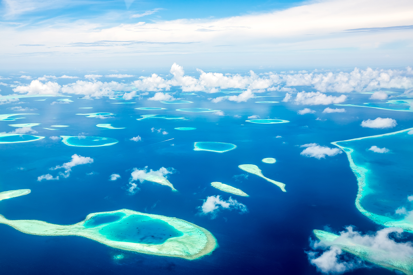 dozens of small atolls scattered across blue water in Maldives