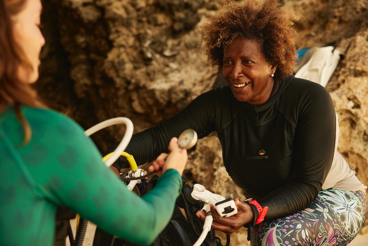 a padi instructor helps a new diver set up their scuba equipment