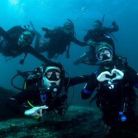A group of five divers underwater smiling and having fun