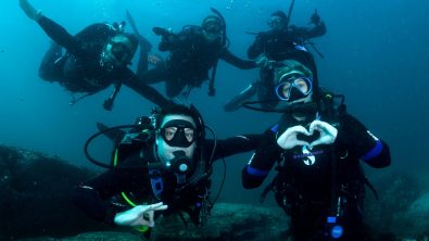 A group of five divers underwater smiling and having fun
