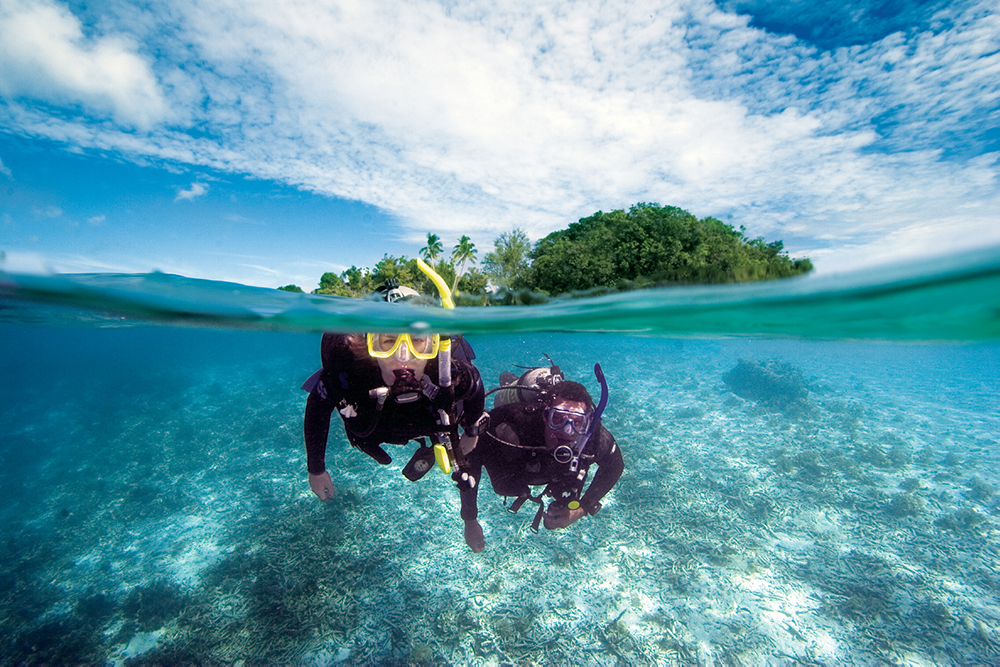 Two divers swimming under the surface at one of many all-inclusive scuba resorts you can book with confidence at PADI Travel